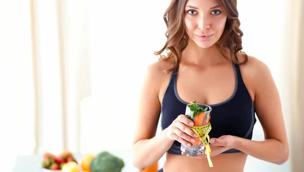 Mulher segurando um copo cheio de salada de frutas frescas com uma fita métrica ao redor do copo — Fotografia de Stock