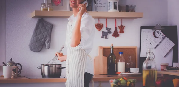 Portret van een lachende vrouw met telefoon in de keuken thuis — Stockfoto