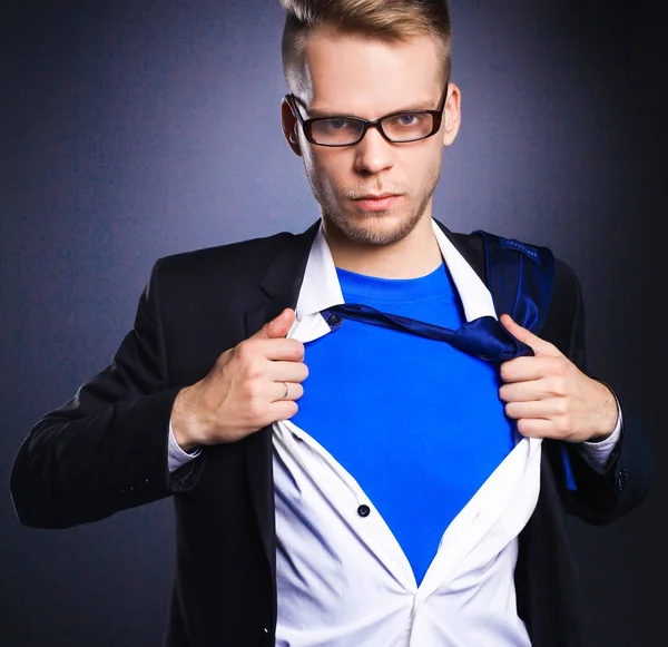 Young businessman acting like a super hero and tearing his shirt, isolated on gray background — Stock Photo, Image