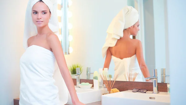 Mujer atractiva joven de pie frente al espejo del baño — Foto de Stock