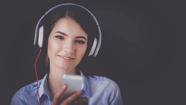 Chica sonriente con auriculares sentados en el suelo cerca de la pared —  Fotos de Stock