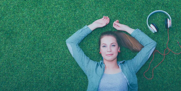 Relaxed woman listening to the music with headphones lying on grass — Stock Photo, Image