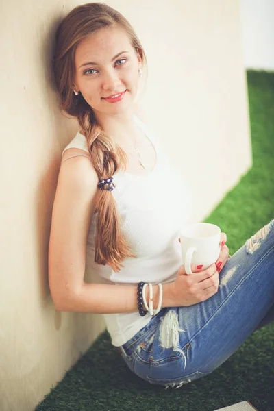 Hermosa mujer sentada en el suelo y sosteniendo una taza. Hermosa mujer —  Fotos de Stock