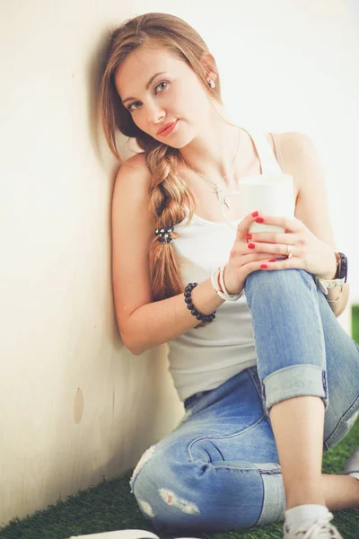 Hermosa mujer sentada en el suelo y sosteniendo una taza. Hermosa mujer — Foto de Stock