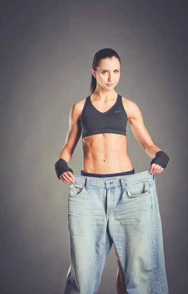 Ung fitness kvinna visar att hennes gamla jeans . — Stockfoto