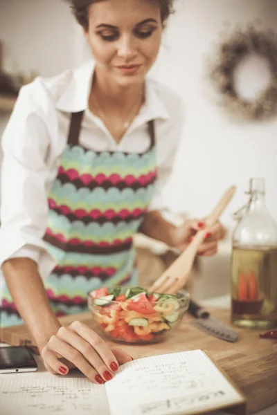 Lachende jonge vrouw voorbereiding salade in de keuken. — Stockfoto