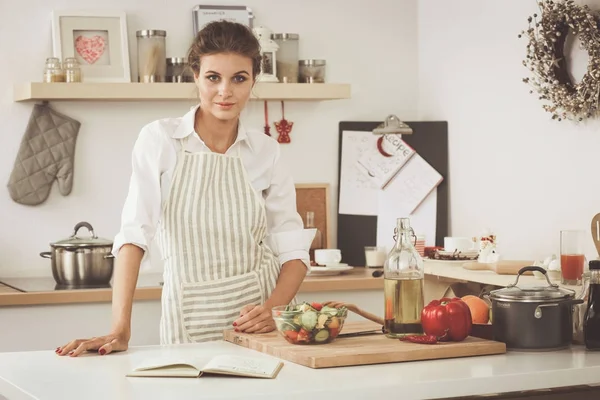 Sorrindo jovem mulher preparando salada na cozinha . — Fotografia de Stock