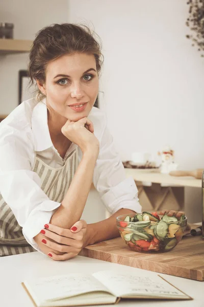 Lachende jonge vrouw voorbereiding salade in de keuken. — Stockfoto