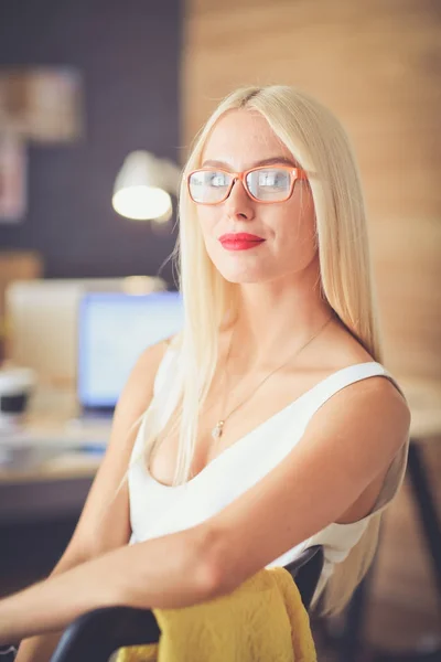 Portrait of an executive professional mature businesswoman sitting on office desk