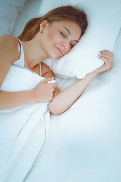 Une belle jeune femme couchée confortablement et joyeusement au lit. — Photo