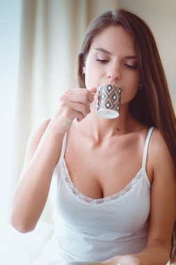 bir bardak süt ile yatakta oturan genç kadın