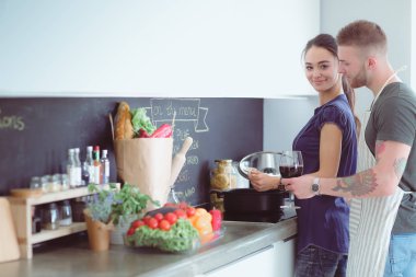 Bir çift evdeki mutfaklarında birlikte yemek pişiriyor.