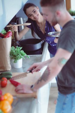 Bir çift evdeki mutfaklarında birlikte yemek pişiriyor.