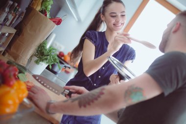 Bir çift evdeki mutfaklarında birlikte yemek pişiriyor.