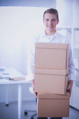 Gri arka plan üzerinde oturan gülümseyen genç adam portresi. Genç adam portresi