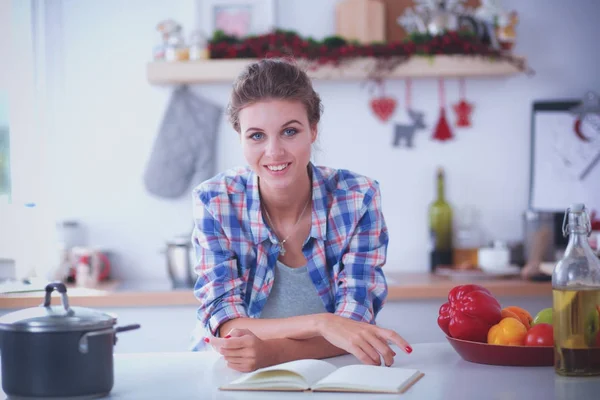 Mulher sorridente a segurar o telemóvel na cozinha. Mulher sorridente . — Fotografia de Stock