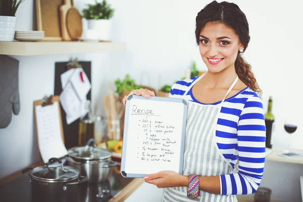 Woman in the kitchen at home, standing near desk with folder. — Stock Photo, Image