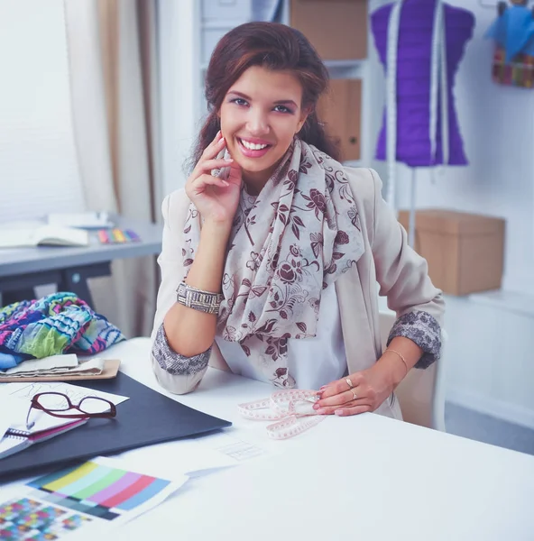 Glimlachende vrouwelijke mode-ontwerper zit aan het bureau — Stockfoto