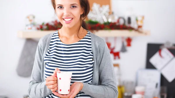 Портрет молодой женщины с чашкой на кухонном фоне. — стоковое фото
