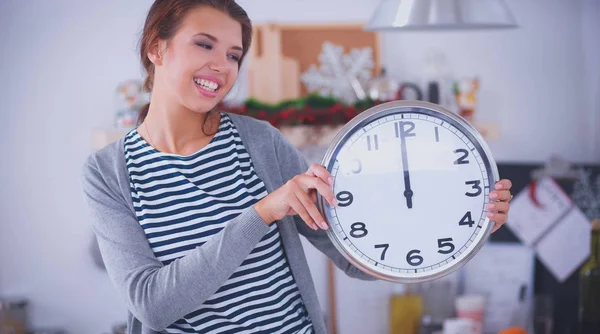 Happy young woman showing clock in christmas decorated kitchen — Stock Photo, Image