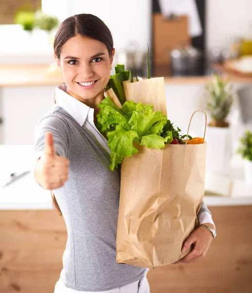 Young woman holding grocery shopping bag with vegetables and showing ok — Stock Photo, Image