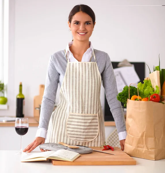 Femme avec des sacs à provisions dans la cuisine à la maison, debout près du bureau — Photo