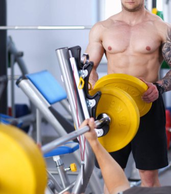 Genç adam eğitmen ile spor salonunda halter kaldırma