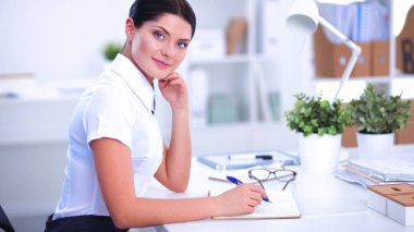 Ofiste masa başında oturan çekici bir iş kadını.