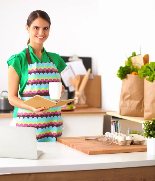 Lächelnde junge Frau in der Küche, isoliert im Hintergrund — Stockfoto