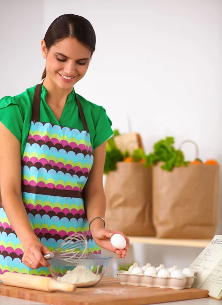 Leende ung kvinna i köket, isolerad på bakgrunden — Stockfoto