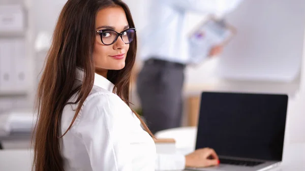 Attractive businesswoman sitting on desk in the office — Stock Photo, Image