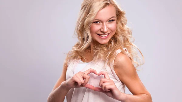 Lachende meisje in witte shirts tonen hart met handen — Stockfoto