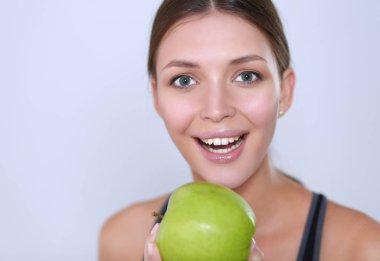 Mutlu genç kadın elma yiyor, beyaz arka planda soyutlanmış..