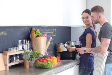 Bir çift evdeki mutfaklarında birlikte yemek pişiriyor.