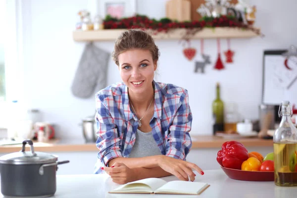 Eine lächelnde Frau hält ihr Handy in der Küche. Lächelnde Frau. — Stockfoto