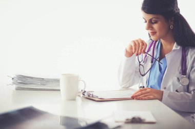 Elinde evrakları olan kadın masanın üstünde oturuyor.