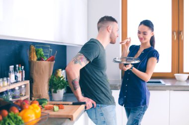 Bir çift evdeki mutfaklarında birlikte yemek pişiriyor.