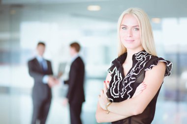 Ofisteki genç iş kadınının portresi ve arka planda meslektaşları. .