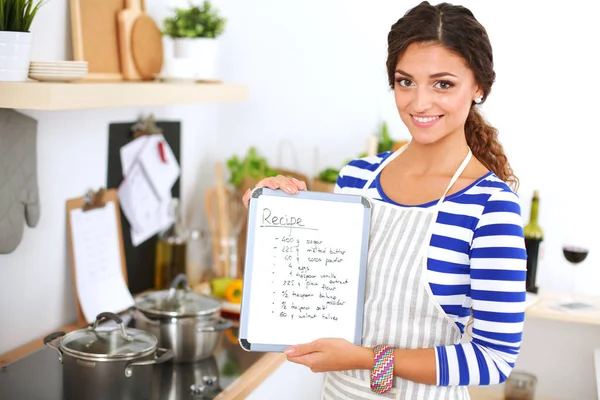 Femme dans la cuisine à la maison, debout près du bureau avec dossier. — Photo