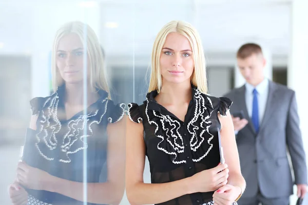 Business woman standing in foreground with a folder in her hands .