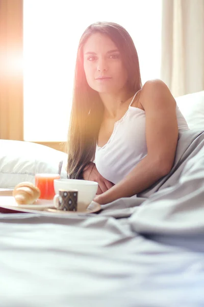 Wanita muda duduk di tempat tidur dengan secangkir susu — Stok Foto