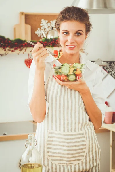 Lachende jonge vrouw voorbereiding salade in de keuken. — Stockfoto