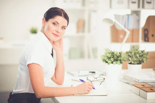 Atrakcyjna bizneswoman siedzi w biurze, odizolowana — Zdjęcie stockowe