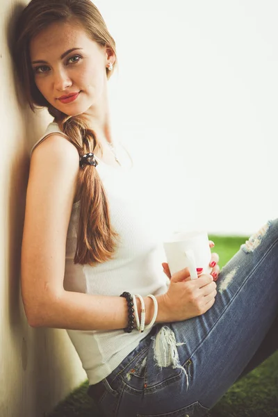 Hermosa mujer sentada en el suelo y sosteniendo una taza. Hermosa mujer — Foto de Stock