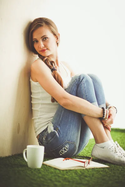 Hermosa mujer sentada en el suelo y sosteniendo una taza. Hermosa mujer —  Fotos de Stock