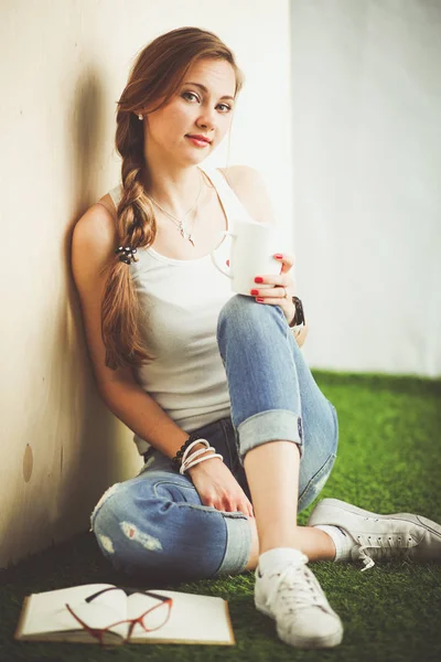 Hermosa mujer sentada en el suelo y sosteniendo una taza. Hermosa mujer —  Fotos de Stock