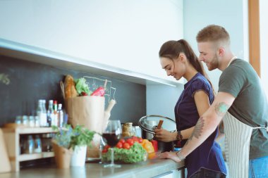 Bir çift evdeki mutfaklarında birlikte yemek pişiriyor.