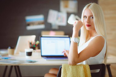 Moda tasarımcıları stüdyoda çalışıyor. Masanın üzerinde oturuyorlar..