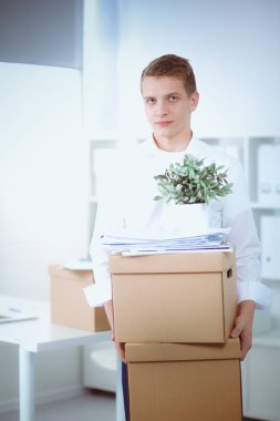 Gri arka plan üzerinde oturan gülümseyen genç adam portresi. Genç adam portresi