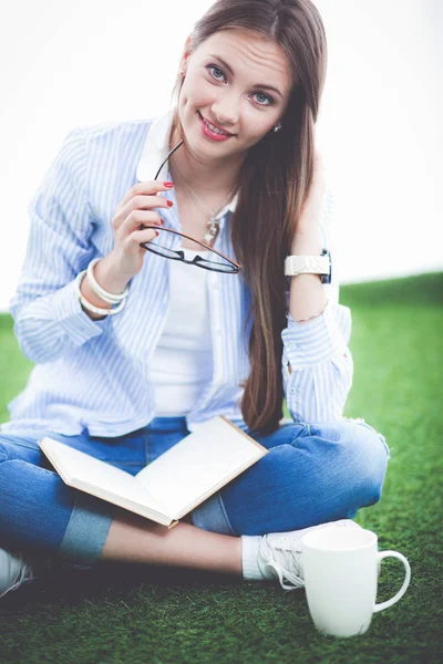 Młoda kobieta siedząca z książki na trawie. Młoda kobieta — Zdjęcie stockowe